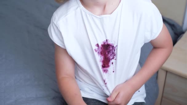 子供はベリーを食べながら部屋のベッドに座っている 白い服に汚れたブルーベリーの汚れ 日常生活の汚れの概念 高品質の写真 高品質の4K映像 — ストック動画