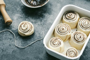 Tarçınlı çörek pişiriyorum. Cinnabon. Çiğ ekmek kızartma kabında yuvarlanıyor. Yüksek kalite fotoğraf