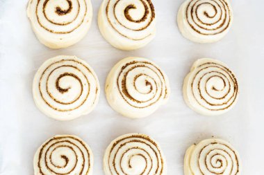 Çiğ, pişmemiş tarçınlı çörekler dinleniyor. Alternatif unlardan sağlıklı çörek pişirmek. Vejetaryen ekmeği. Kutlama yemeği. Üst Manzara. Yüksek kalite fotoğraf