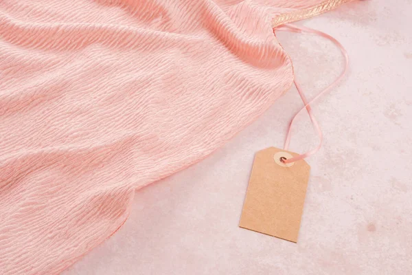 Clothing tag, mock up. Beautiful peach color texture of the clothing. Responsible consumption. Environmental friendliness and sustainable fashion. High quality photo