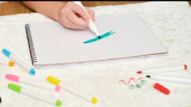 Kağıt üzerinde yeşil keçeli kalemle bir çocuğun el çizimi. Döşeme mobilyalarındaki kirli keçeli kalemler ya da halı. Yüksek kalite 4k görüntü