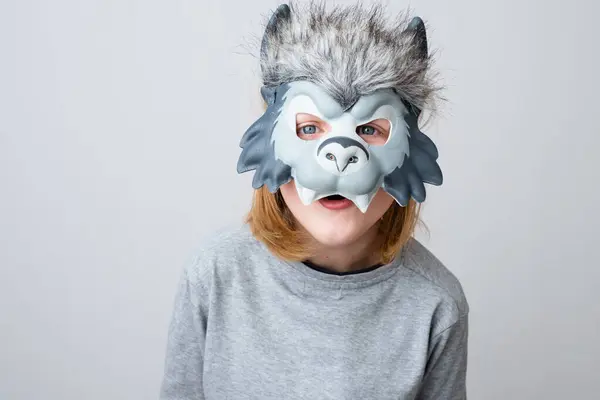 A surprised wolf looking at the camera, isolated on a gray background. Child wearing a wolf mask. Early child development and imagination. High quality photo