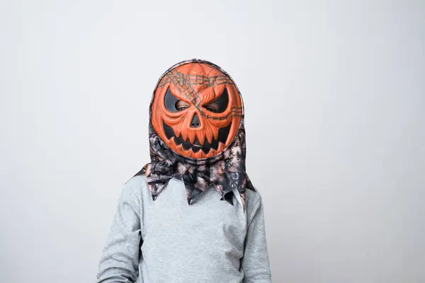 Child wearing pumpkin vinyl mask on a gray background. Halloween holiday or a birthday party. Early child development and imagination. . High quality photo