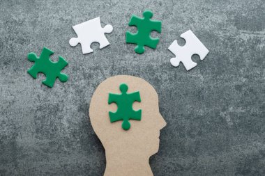 Zihinsel sağlığı, ekolojik endişeyi ve kendine bakımı temsil eden yeşil ve beyaz yapboz parçaları olan bir insan kafası silueti. Çevresel farkındalık ve sürdürülebilirlik kavramı. en üstteki görünüm.