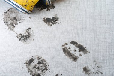 Sarı lastik botlar açık renkli bir yüzey üzerinde belirgin çamurlu ayak izleri oluşturur. Bu da nemli havalarda son zamanlarda açık havada bir aktivite olduğunu gösterir. Yüksek kalite fotoğraf