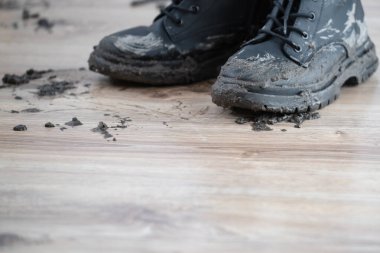 Islak ve çamurlu botlar ahşap bir zemine bırakılır ve arkalarında dağınık bir iz bırakır. Yağmurlu bir günün ardından açık hava keşifleri bellidir. Temizlik ve kirli leke kavramı. Yüksek kalite fotoğraf