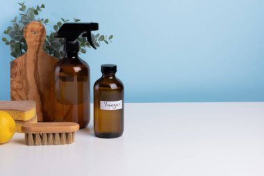 Kahverengi cam temizleme malzemeleri beyaz bir masada sünger, fırça ve taze limonla birlikte oturur ve organize ve davetkar bir temizlik düzeneği oluşturur. Metin için boşluk. Yüksek kalite fotoğraf