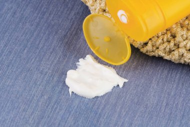 Spilled sunscreen from a yellow tube on clothes or towel. A dirty cosmetic stain on a denim background. The concept of daily stains on clothes. High quality photo clipart