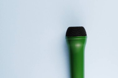 Close up green microphone and bubble foam on a blue background. Deceptive marketing. Greenwashing concept. High quality photo clipart