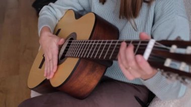 Konforlu bir oturma odasında gitar çalan, çeşitli tıngırtı şekilleri sergileyen, daha düşük görüş açılı bir kişi. Sıcak atmosfer, müziğin tadını çıkarırken rahatlamaya davet eder..