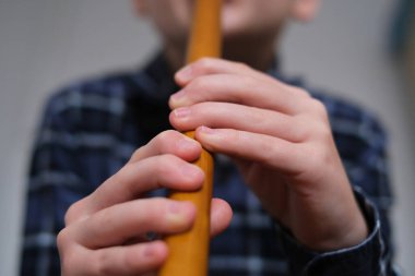 A child playing a wooden reed pipe, showcasing skill and concentration on a gray background, angle of view from below . High quality photo clipart