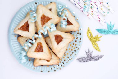 Açık mavi kurdeleler ve dekore edilmiş maskeyle süslenmiş taze pişmiş üçgen kurabiyeleri kapat. Purim kutlaması konsepti. Üst Manzara. Yüksek kalite fotoğraf