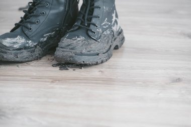 Çamurlu siyah çizmeler ve ahşap zeminde çamurlu ayak izleri büyük bir çamur keki bırakıyor. Islak havada çamur temizleme kavramı. Üst Manzara. Yüksek kalite fotoğraf