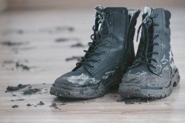 Ahşap zemine bırakılmış çamurlu botları kapayarak büyük bir çamur keki bırakırlar. Yağmurlu bir günün ardından açık hava keşfi çok açık. Islak havada çamur temizleme kavramı. Yüksek kalite fotoğraf