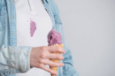 Eriyen mor dondurmayı arka planda waffle külahında beyaz kıyafetlerin kirli lekesinde kapat. Mesaj için yer var. Kıyafetlerdeki günlük lekeler. Yüksek kalite fotoğraf