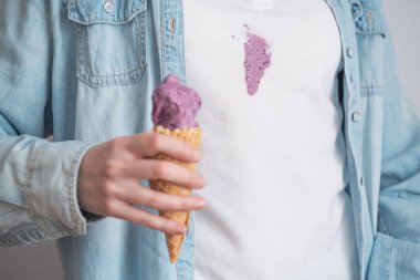 Eriyen mor dondurmayı arka planda waffle külahında beyaz kıyafetlerin kirli lekesinde kapat. Mesaj için yer var. Kıyafetlerdeki günlük lekeler. Yüksek kalite fotoğraf