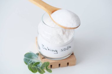 Kabartma tozu etiketli bir kavanoz, tahta bir standın üzerinde, beyaz toz ve doğal ışıklandırmayla dolu tahta bir kaşıkla duruyor. Çevreye duyarlı ve çevre dostu bir seçim. Yüksek kalite fotoğraf