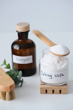 Doğal ev temizlik ürünleri kabartma tozu, kahverengi cam şişeler, beyaz arka planda okaliptüs dalı ile fırça. Yüksek kalite fotoğraf