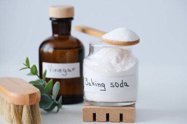 Doğal ev temizlik ürünleri kabartma tozu, kahverengi cam şişeler, beyaz arka planda okaliptüs dalı ile fırça, doğal ışıklandırma. Çevreye duyarlı ve çevre dostu bir seçim.. 