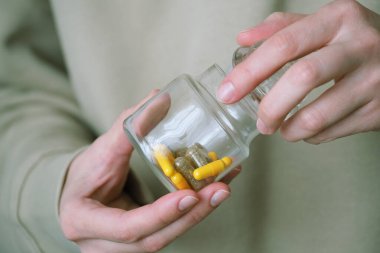 Bir insan cam kavanozu açar. Ağrı kesici, ilaç, vitamin ya da antibiyotik almak için renkli diyet kapsülleri. Farmakolojik hazırlıklar, tıbbi ürünler. Yüksek kalite fotoğraf