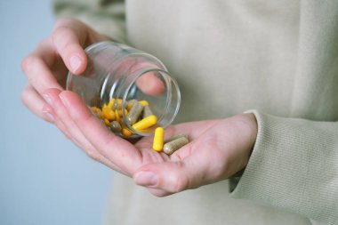 Bir insan eline cam kaplardan rengarenk diyet kapsülleri dökerek ağrı kesici, ilaç, vitamin ya da antibiyotik alır. Tıbbi ürünler. Yüksek kalite fotoğraf