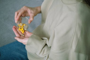 Bir insan eline cam kaplardan rengarenk diyet kapsülleri dökerek ağrı kesici, ilaç, vitamin ya da antibiyotik alır. Sağlık konsepti. Üst Manzara. Yüksek kalite fotoğraf