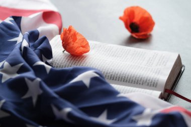 Amerikan bayrağı parlak gelincik çiçeklerini gri arka planda açık bir İncil 'de süsledi.. 
