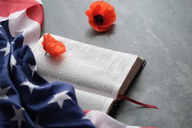 Amerikan bayrağı parlak gelincik çiçeklerini gri arka planda açık bir İncil 'de süsledi.. 