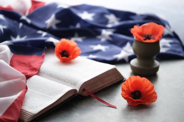 Amerikan bayrağı parlak gelincik çiçeklerini gri arka planda açık bir İncil 'de süsledi.. 
