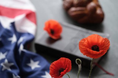 Kapalı bir İncil 'de Amerikan bayrağıyla süslenmiş parlak gelincik çiçekleri gri arka planda challah ekmeğinin yanında. Anma Günü, Gaziler Günü ya da Anma Günü anma Günü. Yüksek kalite fotoğraf