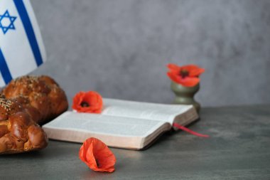 Açık bir kitabın yanına koyulmuş parlak turuncu gelincikler. Yahudi geleneksel kalamar ekmeği. Anma ve umudun sembolü. Savaş anıtı tatili. Yahudi Anma Günleri. - Evet. Yüksek kalite fotoğraf