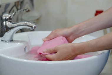 Pembe bezleri lavaboya sokan insanların yakın çekimi. Basit bir dekorla banyoyu hazırlamak. Kıyafetlerdeki günlük lekeler. Yüksek kalite fotoğraf