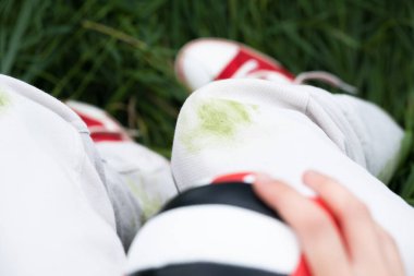 Yaz etkinliği sırasında beyaz kotlardaki kirli çimen lekelerini kapatın. Giysi bakımı ya da leke çıkarma. Kıyafetlerdeki günlük lekeler. - Evet. Yüksek kalite fotoğraf