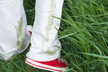 Beyaz kotlar çimen lekeleri ve parlak kırmızı spor ayakkabılar gösteriyor. Açık gökyüzünün altında canlı yeşil bir alanda duran bir insan, açık havada sıcak bir günün tadını çıkarıyor. Yüksek kalite fotoğraf
