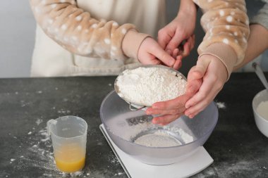  Bir kadının ve oğlunun ellerini kurabiye pişirirken, unu bir kasede ellerken, bayram süsü verilmiş mutfak tezgahında pişirirken. Zevkli bir öğrenme deneyimini paylaşıyorlar. Yüksek kalite fotoğraf