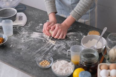 Bir insan hamuru, un, yumurta ve fındık gibi çeşitli fırınlama malzemeleriyle çevrili temiz bir tezgahta yoğurur. Mutfak seti davetkar ve sıcak. Yüksek kalite fotoğraf