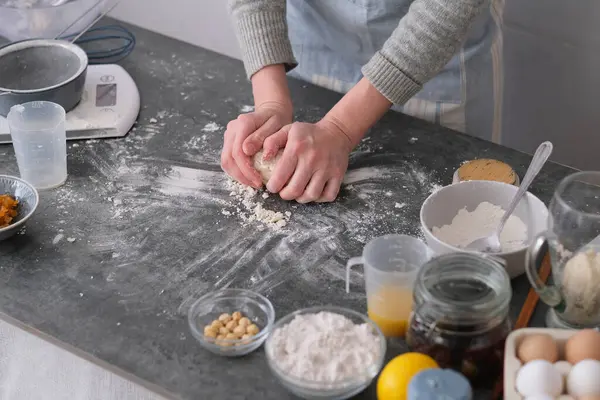 Bir insan hamuru, un, yumurta ve fındık gibi çeşitli fırınlama malzemeleriyle çevrili temiz bir tezgahta yoğurur. Mutfak seti davetkar ve sıcak. Yüksek kalite fotoğraf