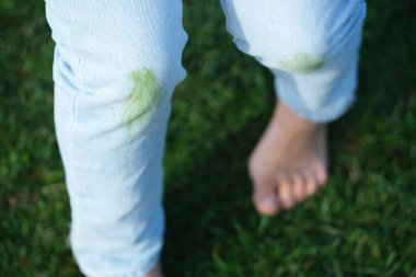 Dirty jeans with grass on their knees are ready for home stain removal. Cleaning supplies such as a brush, sponge, and jars of powder. The concept of eco-friendly stain removal on clothes. top view . High quality photo