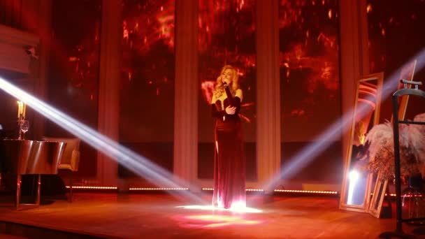 Sahnede Kırmızı Gölgeli Spot Işıklarıyla Mikrofonlu Sarışın Kadın Şarkıcı Burgundy — Stok video