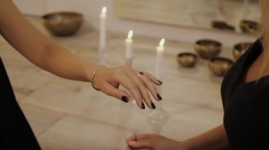 Kadın eli, iyi şans ve huzur getirsin diye kadının bileğine kırmızı bir ip bağlar. Tibet kâselerinin ve yanan mumların arka planına karşı dini ritüel