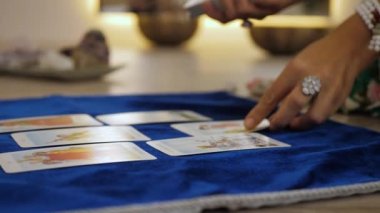 Kristal Gözlemci, mavi halıya tarot kartları serer. Geleceği tahmin etmek için falcılık ritüeli