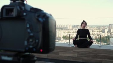 Siyah elbiseli kadın güzellik blogcusu konuşuyor, bacak bacak üstüne atıyor, video konferansına katılıyor, müşterilerle uzaktan pazarlık yapıyor. Çatı katındaki terasta çalışmak ya da ders çalışmak için video eğitimi