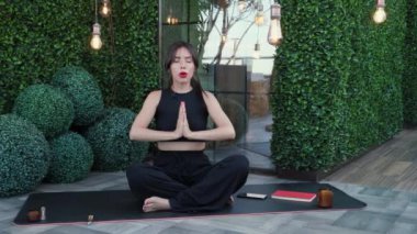 Güzel bir kadın karemat üzerinde bağdaş kurarak oturur, meditasyonu kapalı gözlerle yapar, iç ahengi ve dengeyi hisseder. Video konferansına katılan bir bayan. Çalışma ve öğrenim için video eğitimi