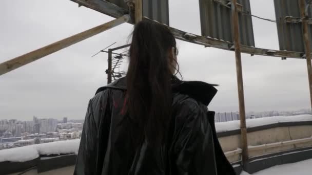黒い光の夏の服の女性は 雪に覆われた屋根の背景に歩いています 高層ビルの屋上に自由の活力を楽しむアジアの女性 カメラを見る — ストック動画