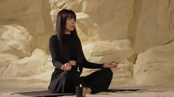 砂漠の砂丘 瞑想を実践する 黒い服の美しい女性は 閉じた目で砂の上のカラマに十字架につけられ 内なる調和とバランスを感じ 自己認識を改善し ストレスフリー — ストック動画
