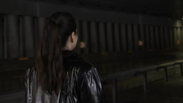 橋の下の黒いライトコートの女性 リアビュー アジアの女性が車で道路の背景に歩く — ストック動画