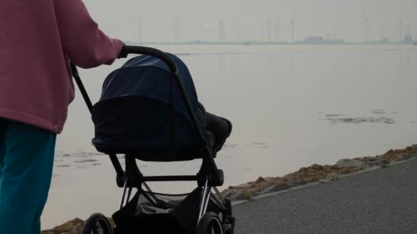 Oigenkännlig Kvinna Med Barnvagn Nära Stranden Viken Med Vindkraftverk Som — Stockvideo
