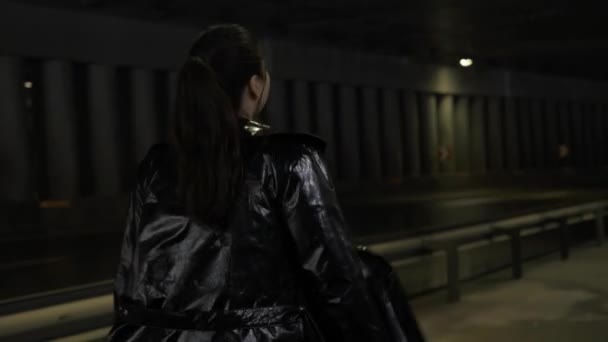 アジアの女性は夜空の道の背景に歩いて走ります 橋の下の黒いライトコートの女性 リアビュー — ストック動画