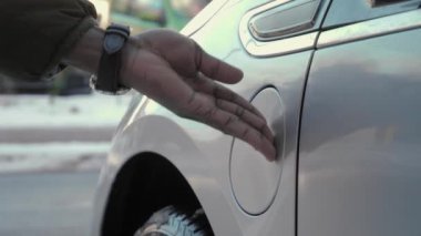 Afrikalı erkek eli EV vagonuna güç bağlantısı yerleştiriyor. Yaklaş. Tanınmayan Afrikalı bir adam elektrikli araca kablo bağlıyor ve kışın yol kenarındaki aküleri şarj ediyor.