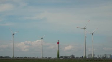 Yeşil yenilenebilir enerji. Rüzgar enerjisi kuleleri inşa ediliyor, otoyolun yakınında birçok rüzgar değirmeni inşa ediliyor. Rüzgar türbini çalışıyor ve yeşil elektrik üretiyor. Bulutlu gökyüzünün altındaki yel değirmeni, boşluğu kopyala